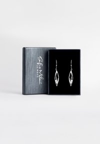 Silverbladformade örhängen i en svart sammetspälsad box med en stilren silverutsida, prydd med intrikata utskurna mönster.