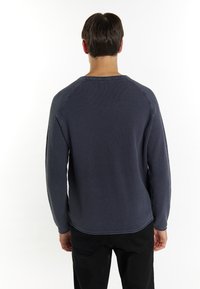 Maglione a maglia blu navy con tessuto testurizzato, maniche lunghe e orlo a coste. Presenta un collo rotondo e un design senza cuciture sulle spalle.