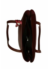 Sarkans teksturēts ādas rokassoma ar divām rokturiem, kurā redzama ar rāvējslēdzēju aiztaisāma iekšējā nodalījuma daļa un dekora šalle, kas piesprausta pie viena roktura.