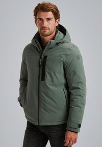 Giacca isolante verde con cappuccio, chiusura frontale con zip e dettagli neri. Presenta una texture liscia e una tasca sul petto per riporre gli oggetti.