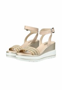 Sandales compensées beiges avec brides à la cheville et boucles, dotées de brides avant embellies et de semelles compensées blanches.