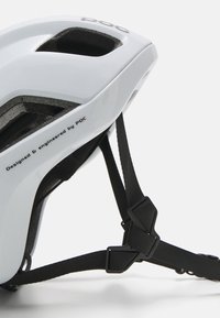 Casco blanco con interior texturizado, recortes para ventilación, correas negras y un hebilla. "Diseñado y fabricado por POC" impreso en el lado.