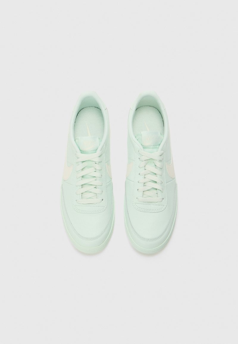 Helle mintgrüne Sneakers mit glatter Textur, ausgestattet mit einem cremefarbenen Nike-Swoosh, runden Schnürsenkeln und einer gepolsterten Sohle.