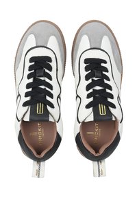 Sneaker in pelle bianca e grigia con lacci neri, dettagli testurizzati e suola in gomma beige. Presentano un logo dorato sulla linguetta.