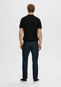 Svart polo skjorte, mørkeblå jeans og svarte joggesko. Poloshirten har krage og korte ermer. Jeansene har smal passform og klassiske lommer.