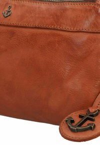 Braune Lederhandtasche mit strukturierter Oberfläche, ausgestattet mit einem metallenen Ankerakzent. Mit Reißverschlussverschluss und sichtbaren kontrastierenden Nähdetails.