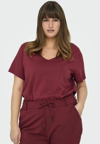Bordeaux V-hals t-shirt van zachte stof, met korte mouwen en een comfortabele pasvorm, gecombineerd met bijpassende hoge broek met een trekkoord.