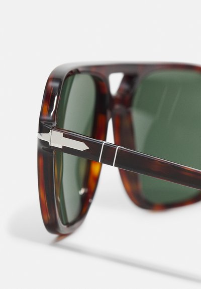 Sonnenbrille mit Schildpatt-Rahmen, dunkelgrünen Gläsern und silbernem Akzent an den Schläfen. Sauberes, kantiges Design mit polierter Oberfläche.