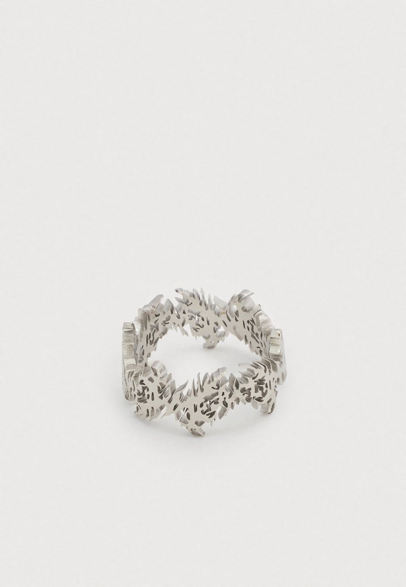 Silver ring with an intricate cut-out fern leaf pattern forming a continuous band on a white background.