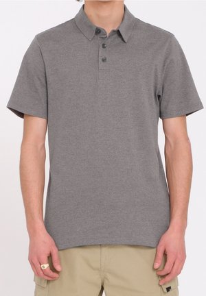 Polo gris à manches courtes avec un col, patte de boutonnage à trois boutons et un logo discret. Le tissu semble lisse avec une texture légère.