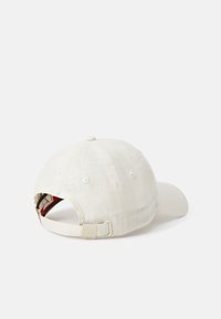 Gorra de béisbol de color claro con una tela texturizada, correa ajustable en la parte trasera y un botón reforzado en la parte superior.