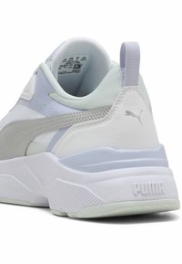 Sneaker bianchi e grigio chiaro con una tomaia in pelle texture e rete, colletto imbottito, suola bianca spessa e un logo discreto sul tallone.