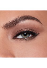 Närbild av ett öga med en gradient av brunt och guld ögonskugga, tydlig svart eyeliner och fylliga ögonfransar som framhäver den gröna iris.