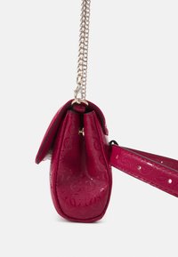 Lille lyserød håndtaske med en blank overflade, der har et tekstureret design, en kæde-rem og en struktureret, rund form.