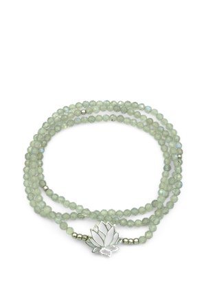 Hellgrüne facettierte Perlenkette mit einem silbernen Lotosblumen-Anhänger auf weißem Hintergrund, locker in einem Kreis angeordnet.