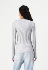 Grå ribbet langermet topp med rund hals, med vertikale striper og tettsittende design, kombinert med lyseblå denimjeans.