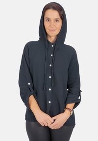 Dunkelblaues Kapuzenshirt aus strukturiertem Stoff, mit Knopfleiste, verstellbaren Ärmeln und lässiger Passform.