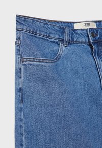 Jeans de mezclilla azul con un diseño clásico de cinco bolsillos, costuras visibles y una textura sutil. La tela parece ligeramente desgastada.