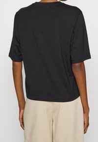 Sort kortærmet T-shirt med en afslappet pasform, fremhævet af en rund halsudskæring og en glat bomuldsstruktur. Bagudsigten viser ingen synlige mønstre eller detaljer.