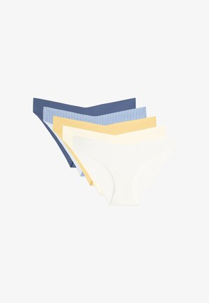 Vrouw draagt naadloos, hoog uitgesneden blauw ondergoed, getoond van taille tot bovenbenen tegen een lichte achtergrond.