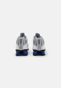 Laufschuhe mit einem grauen und weißen Obermaterial, blauen Akzenten, belüfteten Seitenpanelen und einem einzigartigen, federnden blauen Sohlen-Design.