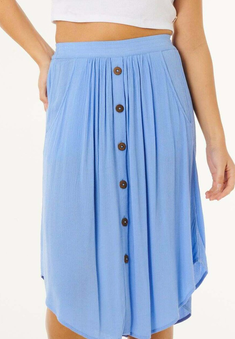 Lichtblauwe midi-rok met hoge taille, houten knopen aan de voorkant, zijzakken, plooien en een licht asymmetrische zoom, gedragen met een wit cropped topje.