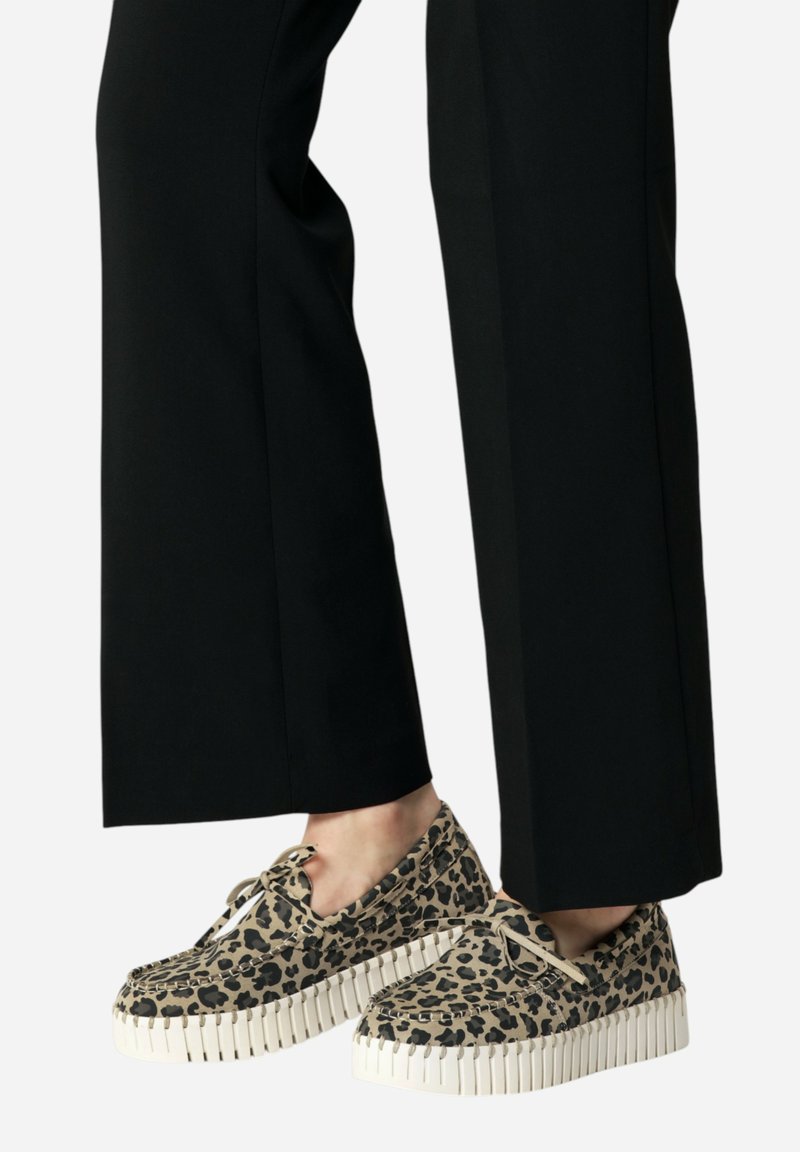 Zapatos de estampado de leopardo con una suela de goma blanca gruesa. Diseño de cordones, con un tejido texturizado y punta redonda. Combinados con pantalones negros.