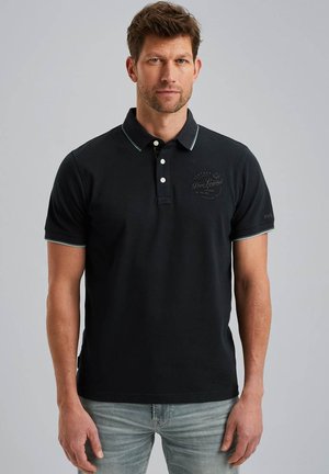 Mornarsko polo majica s tri gumba, tankim zelenim akcentima i izvezеним logotipom na prsima. Kratki rukavi i regularna kroja.