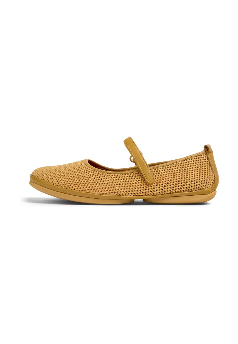 Zapatos planos amarillos perforados con puntera redonda, correa ajustable y suela de goma flexible, que presentan una superficie texturizada.