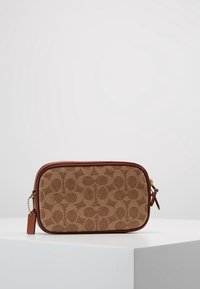 Petit sac en tissu marron avec un motif monogramme, doté d'une bordure en cuir marron, d'une fermeture éclair dorée et d'un charm amovible. Forme rectangulaire, texture lisse.