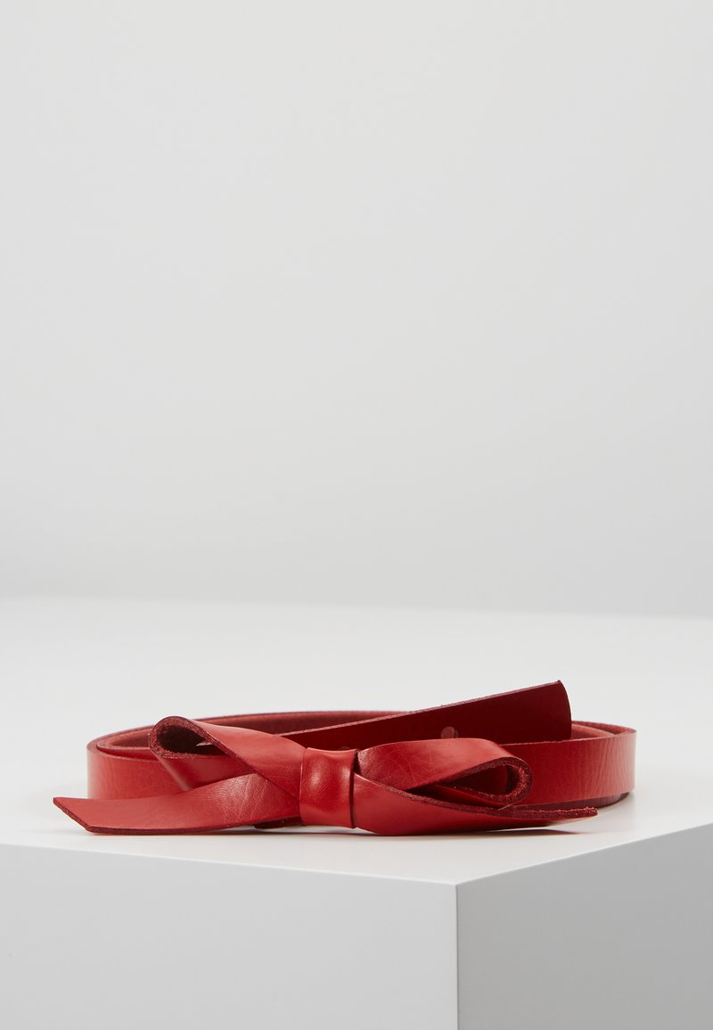 Cinto in pelle rossa con una texture liscia e un dettaglio a fiocco nella chiusura. Forma piatta ed allungata, che mostra un design minimalista.