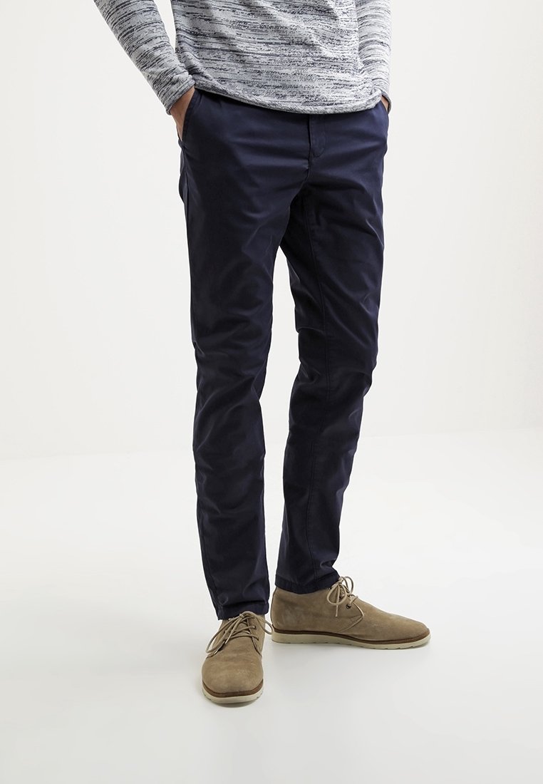 Námořnické kalhoty ve slim fit, vyrobené z hladké látky. V kombinaci s světle hnědými semišovými botami a texturovaným šedým svetrem.