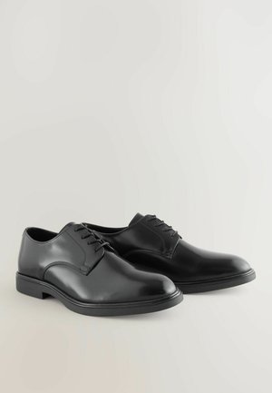 Black leather dress shoes with a smooth finish, rounded toe, five lace eyelets, and a low rubber heel. Simple design, no visible patterns or accents.
