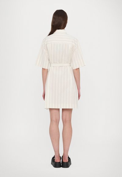 Lühikeste varrukatega triibuline kleit, millel on vöökoht, millel on vertikaalsed beežid ja pastelltooni triibud, valmistatud kerge kangaga. Mustad platvormkingad.