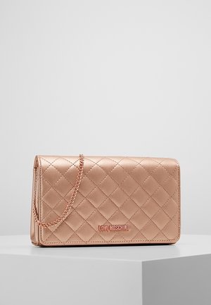 Quiltet satinrosa clutch taske med kæderem og "LOVE MOSCHINO" logo på forsiden, placeret på en grå overflade mod en ensfarvet baggrund.