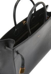 Svart läderhandväska med två rundade handtag, guldfärgad hårdvara och ett läderrem med detalj i form av ett guld lås.