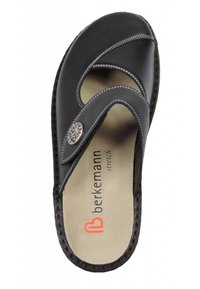 Black leather slide sandal with a thong design, featuring a decorative silver accent and tan insole. Contrasting stitching detail visible.