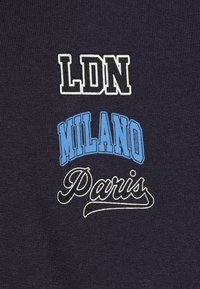 Mornarska tkanina s otisnutim tekstom: "LDN" u bijelom, "MILANO" u svijetloplavoj, i "Pariz" u kurzivnom bijelom, s teksturiranim pletenim pozadinom.