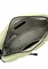 Interior de un bolso de mano acolchado de color verde claro con un forro gris, cierre de cremallera y múltiples compartimentos para la organización. Acentos de tela texturizada.
