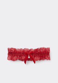 Cinta de liga roja de encaje con volantes reunidos, un lazo de cinta de satén y un pequeño charm decorativo. Presenta patrones florales y un detalle delicado.