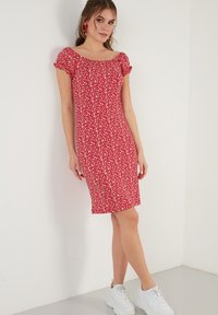 Red floral dress with short ruffled sleeves, knee-length hem, cotton fabric, and white sneakers. The pattern features small white flowers.