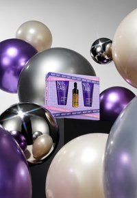 Ensemble de soins NIP+FAB dans une boîte violette et blanche, comprenant deux tubes et un flacon compte-gouttes. Entouré de ballons brillants en argent, violet et crème.