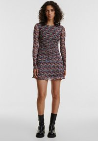 Mini-jurk met bloemenpatroon en lange mouwen, met een aansluitend ontwerp, gerimpelde textuur en een rucheszoom. Kleuren zijn onder andere rood, blauw en geel op een donkere achtergrond.