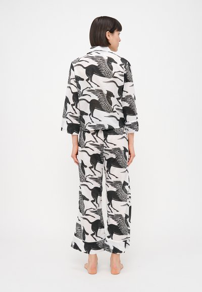 Πυτζάμα σε μαύρο και άσπρο σχέδιο που περιλαμβάνει μακρυμάνικη μπλούζα και παντελόνι με φαρδιά πόδια, κατασκευασμένη από ελαφρύ ύφασμα, με χαλαρή εφαρμογή.