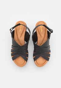 Sandales en cuir noir avec plusieurs larges sangles et un design ouvert à l'avant. Semelle intérieure en cuir brun rembourrée avec perforations. Sangle de cheville ajustable.