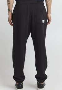 Zwarte sweatpants van zacht stof, met een elastische tailleband, geribbelde boorden en een achterzak met een klein label.