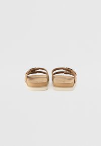 Sandales en cuir marron avec deux brides réglables et une semelle intérieure rembourrée. Semelle en caoutchouc blanche, design minimaliste et texture lisse.