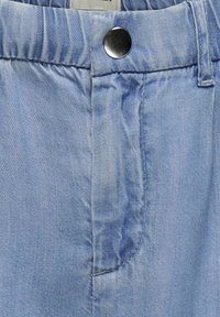Svijetloplave denim traperice s glatkom teksturom, metalnim zatvaranjem na gumb i ravnim pojasom s suptilnim detaljima šivanja.