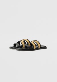 Sorte sandaler med vevde beige detaljer, med to brede stropper og en flat såle. Glatt svart materiale med en teksturert vevd detalj.