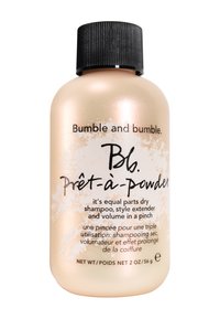 Frasco de champú seco Bumble and bumble Prêt-à-Powder, de un suave color dorado con una tapa negra acanalada, presenta texto en negro y una etiqueta en inglés y francés.